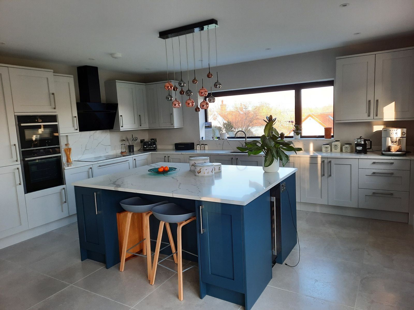Kitchen with a navy island and pendant lights